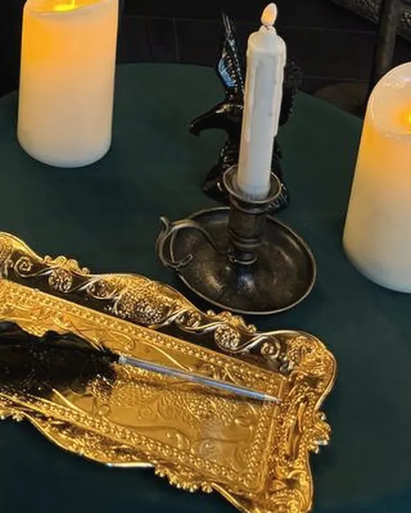 A golden tray with a quill and letter knife, candles on green velvet